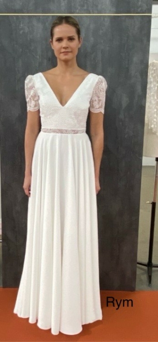 Robe de mariée «Rym» de chez Lambert Création. Cette robe de mariée en dentelle et crêpe et en création et fabrication 100% Français. Cette pépite est disponible dans votre boutique Rêve d'un Jour à Yvetot