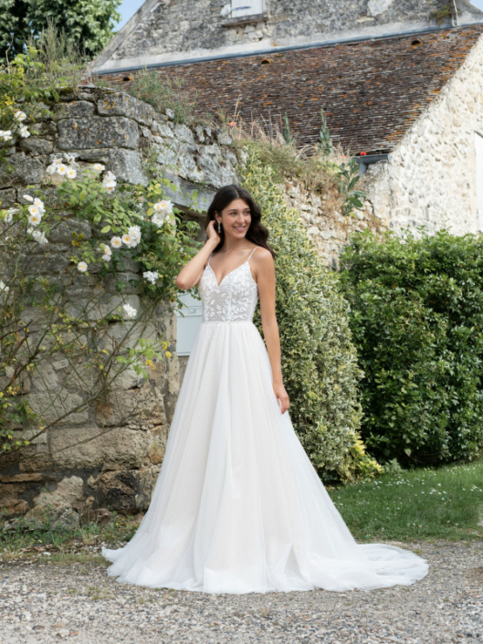 Robe de mariée «Leslie» de chez Framboise Paris. Cette robe de mariée est confectionnée en dentelle Plumetis sur le buste et d’un tulle souple en Plumetis sur la jupe avec une fermeture en V. Style trapèze ou princesse selon le cerceau. Cette robe de mariée est disponible dans votre boutique Rêve d'un Jour à Yvetot