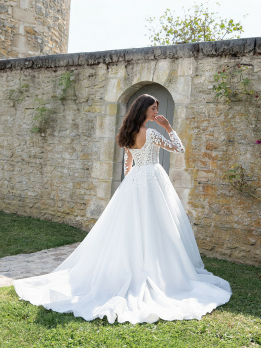 Robe de mariée «Nora» de chez Framboise Paris. Cette robe de mariée est confectionnée en dentelle sur le buste avec des manches et d’un tulle souple paillette sur la jupe avec une fermeture en lacet. Style trapèze ou princesse selon le cerceau. Cette robe de mariée est disponible dans votre boutique Rêve d'un Jour à Yvetot