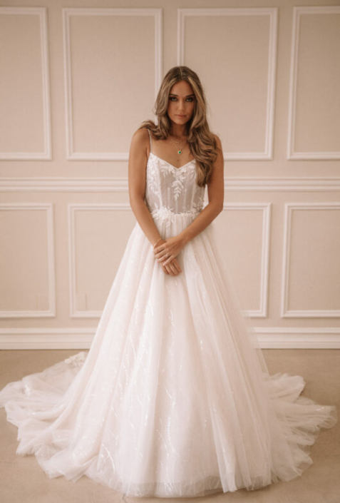 Robe de mariée «Isabelle» de chez Evelyne Bridal. Cette robe de mariée est en dentelle sur le buste et en tulle et sequins sur la jupe et une jolie traine brodée. Disponible en Ivoire et en nude. Cette robe de mariée est disponible dans votre boutique Rêve d'un Jour à Yvetôt